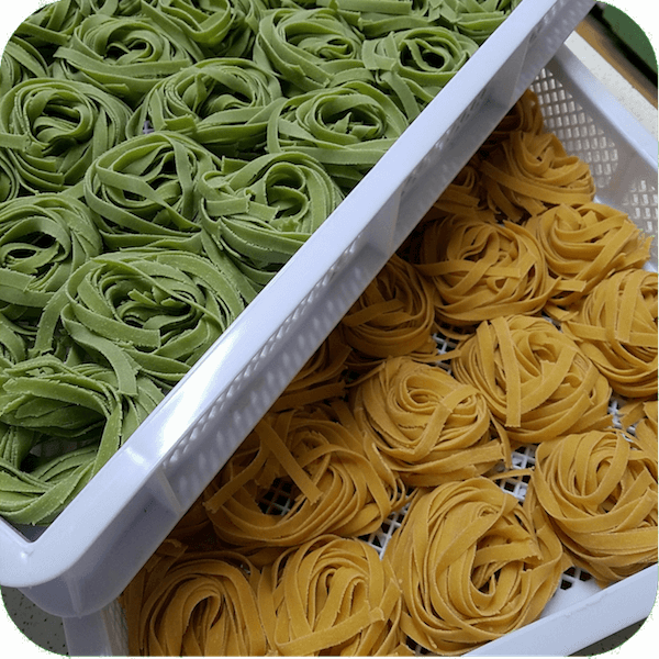 two trays of green and white fettuccine